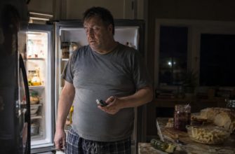 Мужчина ночью измеряет сахар возле открытого холодильника